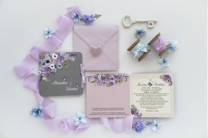 invitatie cu flori pictate mov si albe pe fundal gri si roz