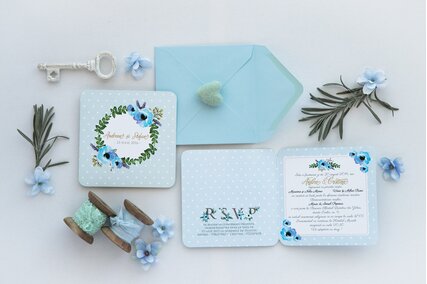 invitatie de nunta albastra cu buline albe si coronita de flori albastre cu frunze