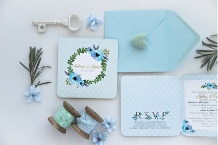 invitatie de nunta albastra cu buline albe si coronita de flori albastre cu frunze