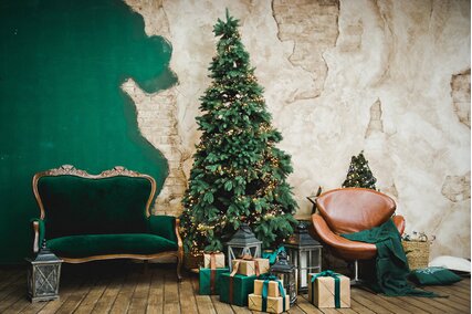 fundal de craciun cu perete verde si canapea langa bradul cu cadouri